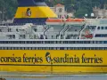 Żółty prom "Corsica Ferries Sardinia Ferries" z ludźmi na pokładzie, gotowy do podróży motocyklem na Sardynię.