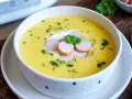 Cremige Kartoffelsuppe, zubereitet im Thermomix, garniert mit Würstchenscheiben, einem Klecks Sahne und Petersilie.