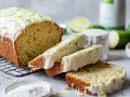Delicioso pastel de calabacín con glaseado blanco y ralladura verde, acompañado de limas frescas.