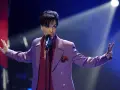Prince w fioletowej marynarce śpiewa na scenie. Jego śmierć była szokiem dla fanów.