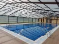 Una piscina cubierta con techo transparente y paredes de cristal, ideal para disfrutar todo el año. Estos porches para piscinas ofrecen un espacio acogedor.