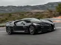 Czarny Bugatti La Voiture Noire pędzi po krętej drodze, otoczony przez górzysty krajobraz.