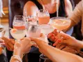 Frauen stoßen mit bunten Cocktails an. Ein fröhlicher Anlass für Day Drinking mit Freundinnen.