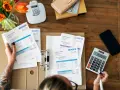 Manos revisando facturas y calculando el total. Aprende como hacer una factura a mano.