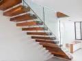 Nowoczesne, drewniane schody z szklaną balustradą. Idealny preparat na skrzypiące schody, by cieszyć się ciszą.