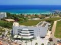 Widok z lotu ptaka na hotel Margadina Lounge Hotel z basenem i palmami, w tle błękitne morze i plaża.