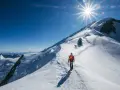 Bergsteiger auf dem Weg zum Gipfel des Mont Blanc. Die Sonne strahlt vom klaren blauen Himmel.