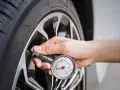 Controllo della pressione gomme 185/65 r15 con manometro. La mano tiene lo strumento attaccato alla valvola.