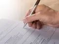 Dłoń z długopisem wypełnia formularz, zaznaczając odpowiedzi. To część procesu tworzenia wykazu majątku.