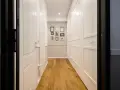 Corridoio con parquet e armadi bianchi. Un'idea per come dividere un corridoio lungo con porte e quadri decorativi.
