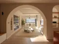 Amplio salón con entrada recibidor integrado. Dos sillones blancos, mesa de centro y sofá invitan a la relajación.