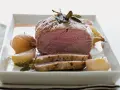 Succulento filetto al forno, cotto alla perfezione con cipolle e erbe aromatiche, servito su un piatto bianco.