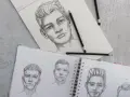 Un dégradé avec dessin de visages d'hommes au crayon. Des croquis de portraits sur un carnet ouvert, avec des crayons posés.