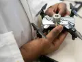 A person holds a small drone with weights attached, perhaps testing its flight capabilities in relation to Oklahoma drone laws.