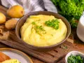 Cremiger Kartoffelbrei, perfekt zubereitet im Thermomix, garniert mit Petersilie. Dazu frische Kartoffeln und ein Glas Milch.