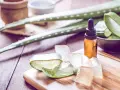 Aloe Vera Gel und Öl auf Holzbrett. Viele fragen sich, ob Aloe Vera gegen Pickel hilft. Hier sind die Zutaten für eine natürliche Hautpflege.