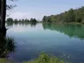 Idyllischer ersinger badesee mit grünen Ufern und einem Kirchturm in der Ferne.