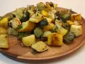 Délicieux courgettes au four, coupées en dés et parsemées de thym frais sur un plat en bois.