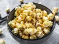 Un bol rempli de pop corn sucré, avec quelques grains éparpillés autour. Un délice croustillant pour une soirée cinéma.