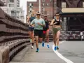 Grupa biegaczy w różnym tempie pokonuje trasę. Intensywny fartlek run na moście miejskim.