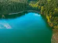 Turkusowe jezioro otoczone lasem, jakby ukryte w okolicach Międzyzdrojów.