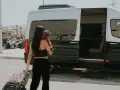 Frau mit Hund und Koffer steigt in Mykonos in einen Van. Ein typischer Anblick auf Reisen über Griechenland.