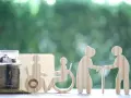 Skarbonka z monetami i drewniane figurki symbolizujące wsparcie dla osób starszych i niepełnosprawnych. Świadczenie wspierające punkty to szansa na lepsze jutro.