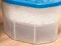 Luftentfeuchter Granulat wird hart, wenn es Feuchtigkeit aufnimmt. Der Behälter zeigt, wie das Granulat die Luft trocknet und sich unten Wasser sammelt.