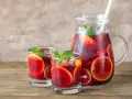 Dwa szklanki i dzbanek pełne orzeźwiającej Sangrii czerwonej z plasterkami pomarańczy i limonki, ozdobione miętą. Idealny wybór na lato!