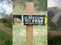 Segnale del sentiero dell'orso nel Parco Nazionale della Maiella, con un sentiero sterrato e montagne sullo sfondo.