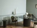 Ett runt matbord med mörka stolar skapar en inbjudande atmosfär. Utrymme runt matbordet ger plats för samtal och gemenskap.