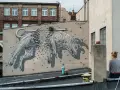 Niesamowite street art graffiti przedstawiające psa rozpadającego się na kamienie. Dzieło sztuki miejskiej na ścianie kamienicy.