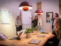 Ett team diskuterar strategier vid ett konferensbord med flera laptops. En kvinna pekar på en trattmodell på en whiteboard. Ups datorn är en del av deras effektiva arbetsflöde.