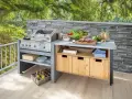 Moderne Grillecke im Garten mit Edelstahlgrill, Arbeitsplatte, Holzschränken und frischen Zutaten. Tolle Garten Ideen für Grillmeister.