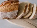 Chleb żytni na drożdżach, pokrojony w kromki, prezentuje się apetycznie na drewnianej desce.