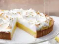 Eine köstliche Tarte au Citron mit fluffiger Baiserhaube, die auf einem Tortenständer präsentiert wird.
