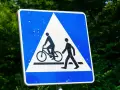Znak ostrzegawczy: przejazd rowerowy i przejście dla pieszych. Czy rowerzysta ma pierwszeństwo na przejeździe rowerowym? Tak, ten znak informuje o tym.