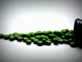 Zielone tabletki chlorelli rozsypane z czarnego pojemnika. Kiedy je brać: chlorella rano czy wieczorem?