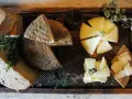 Tabla de quesos variados, hierbas aromáticas y ajos sobre madera.