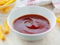 Una ciotola di ketchup fatto in casa, pronto per intingere bastoncini di polenta dorati.