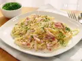 Espaguetis con nata, cubiertos de trocitos de bacon y perejil picado. Un plato cremoso y delicioso.