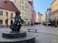 Fontanna z postacią Baccha na brukowanym placu, otoczona kolorowymi kamienicami. Zielona Góra atrakcje turystyczne.