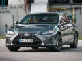 Elegancki, ciemnoszary Lexus 300h z brązowym wnętrzem stoi na parkingu.