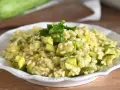 Un cremoso risotto con zucchine, guarnito con prezzemolo fresco, pronto per essere gustato.