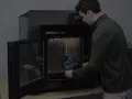 Mężczyzna wkłada wydrukowany model do drukarki 3D Stratasys F120. Tak wygląda drukarka 3d w akcji.