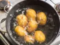Mehrere ganze Kartoffeln kochen in einem Topf mit sprudelndem Wasser auf dem Herd.