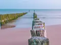 Drewniane pale tworzą ścieżkę wzdłuż plaży, prowadzącą w stronę morza. To idealne miejsce na spacer, odkrywając kąty rybackie trasę.
