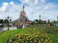 Disneyland Paris castle with colorful flowers and crowds of people.