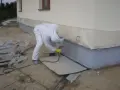 Pracownik w białym kombinezonie maluje fundamenty na kolor przypominający rubinowy.