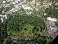 Widok z lotu ptaka na zielony park otoczony drogami, z budynkami mieszkalnymi w tle. To największe rondo w Polsce, które otacza serce miasta.